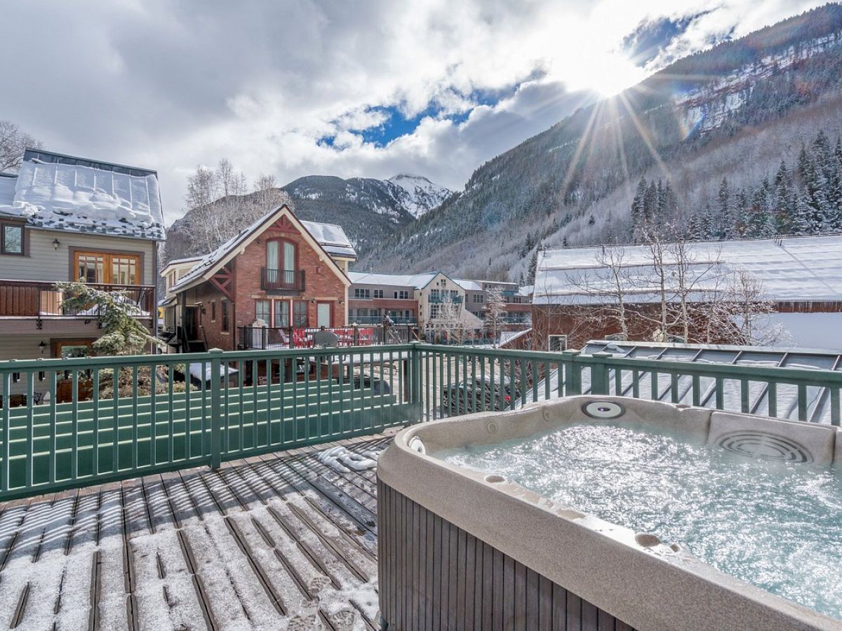 A hot tub on a snowy Hotel Columbia Telluride deck with mountain views and charming houses.