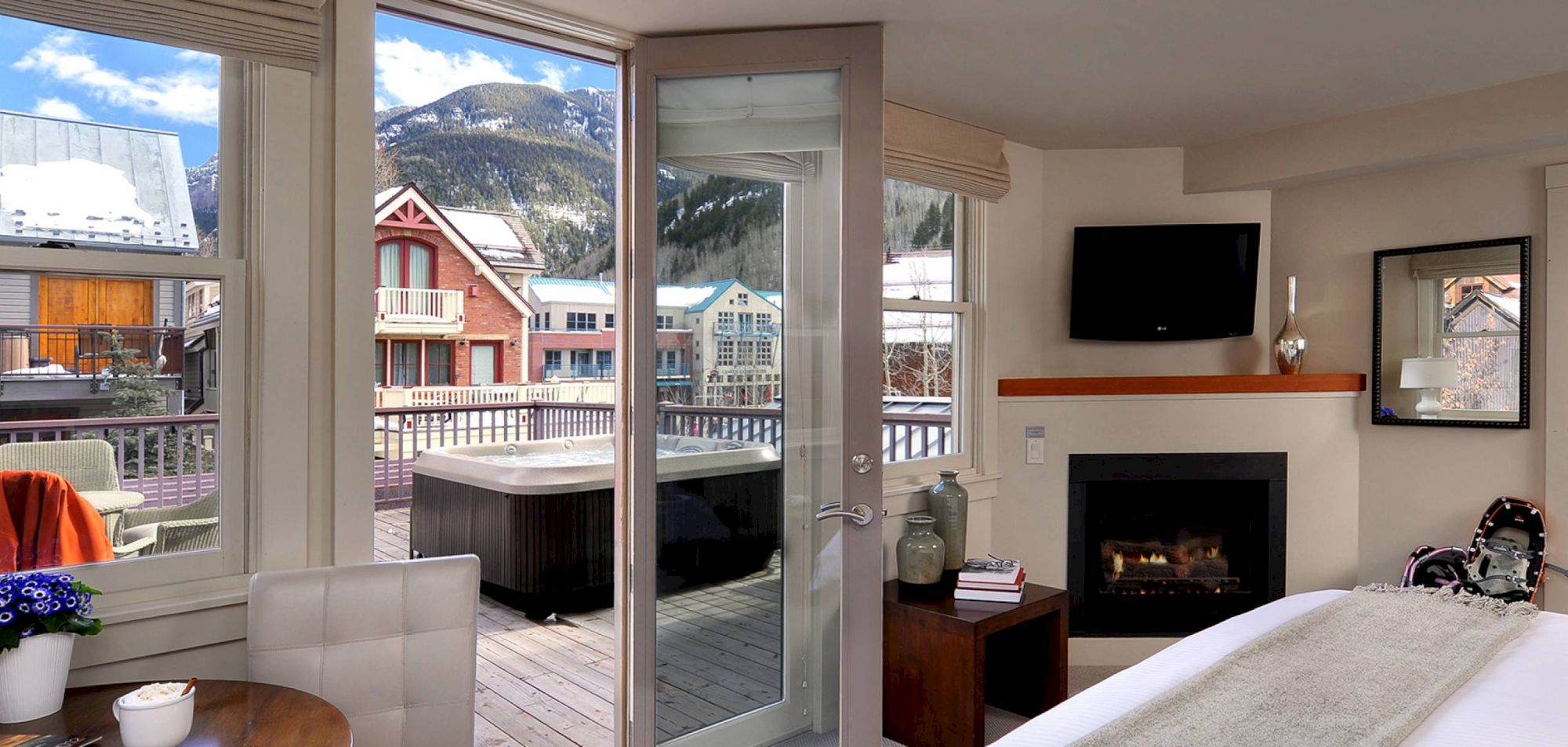 Hotel Columbia Telluride room with bed, fireplace, TV, balcony view of mountains, and outdoor hot tub.