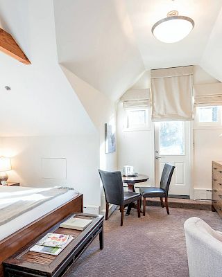 A cozy Hotel Columbia Telluride bedroom with a slanted ceiling, a fireplace, and simple decor.