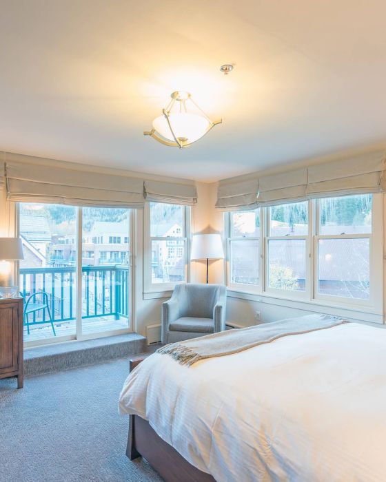 Bright Hotel Columbia Telluride bedroom with a bed, dresser, TV, and balcony access with natural light.