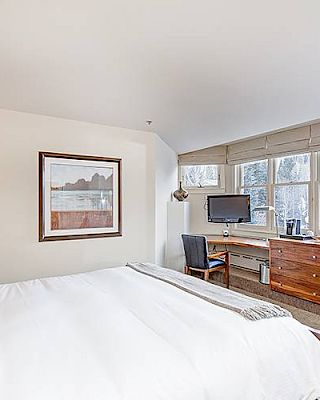 Hotel Columbia Telluride Bedroom with bed, desk, chair, artwork, and natural light.