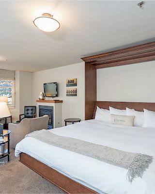 A cozy Hotel Columbia Telluride bedroom setup with a large bed, seating area, and modern amenities.