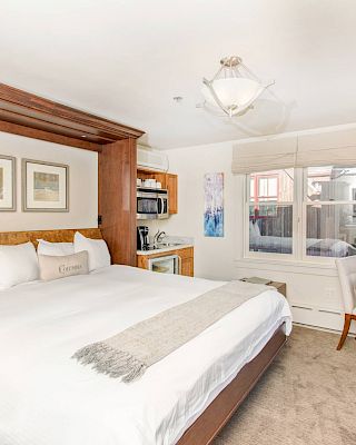 A well-lit Hotel Columbia Telluride bedroom with a large bed, side tables, lamps, artwork, and a window.