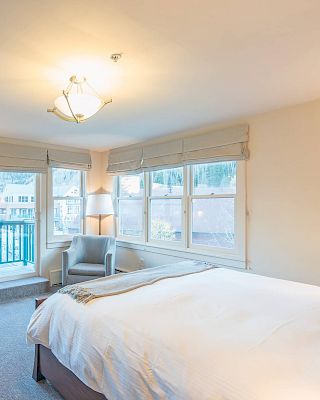 Bright Hotel Columbia Telluride bedroom with a bed, dressers, TV, and a balcony with daylight coming in.