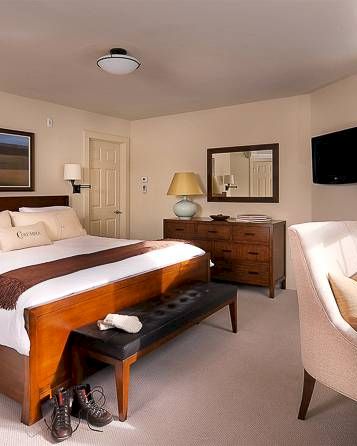 Cozy bedroom with a large bed, side tables, armchair, dresser, and mounted TV.