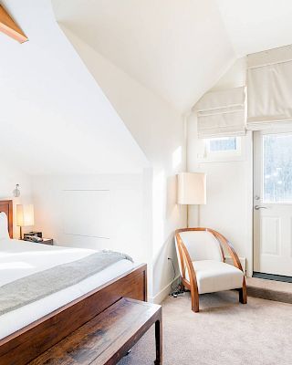 Bright, cozy bedroom with a large bed, dresser, and slanted ceiling.