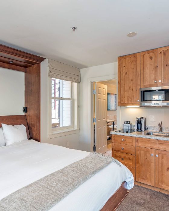 Studio apartment with bed, kitchenette, and wooden cabinets.