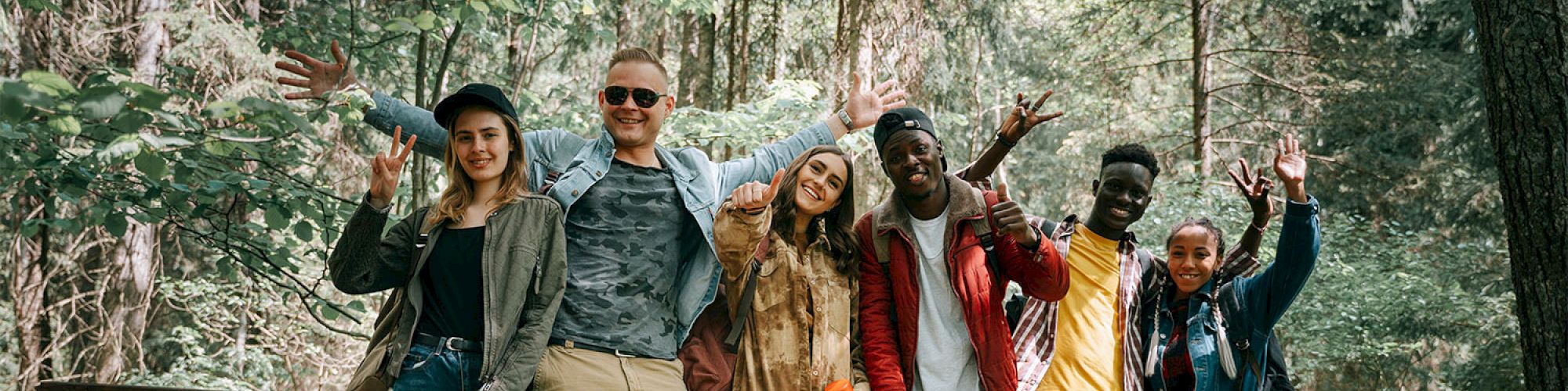 A group of friends posing happily on a bridge in a forest.