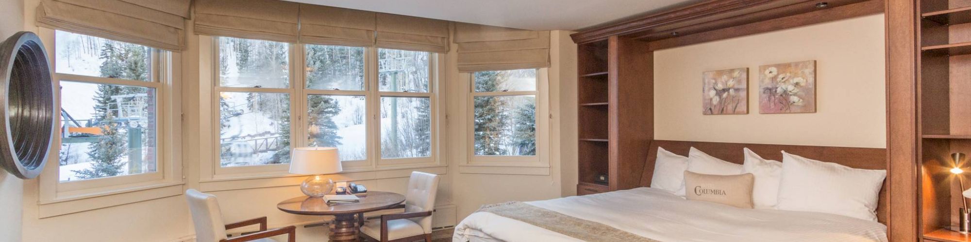 Cozy bedroom with a large bed, wooden furniture, and a view through the window.