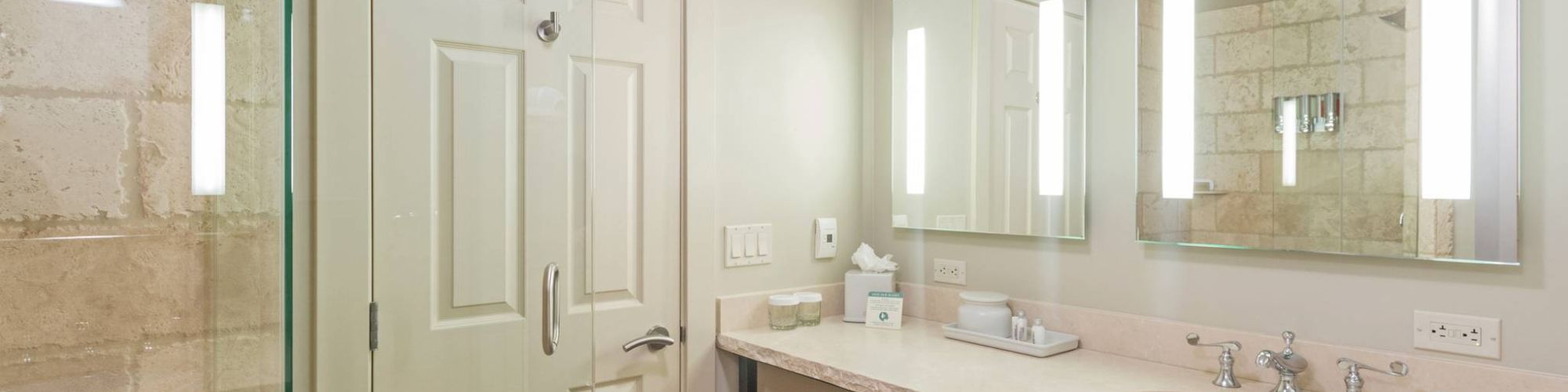 A modern bathroom with a shower, sink, mirror, and towels.