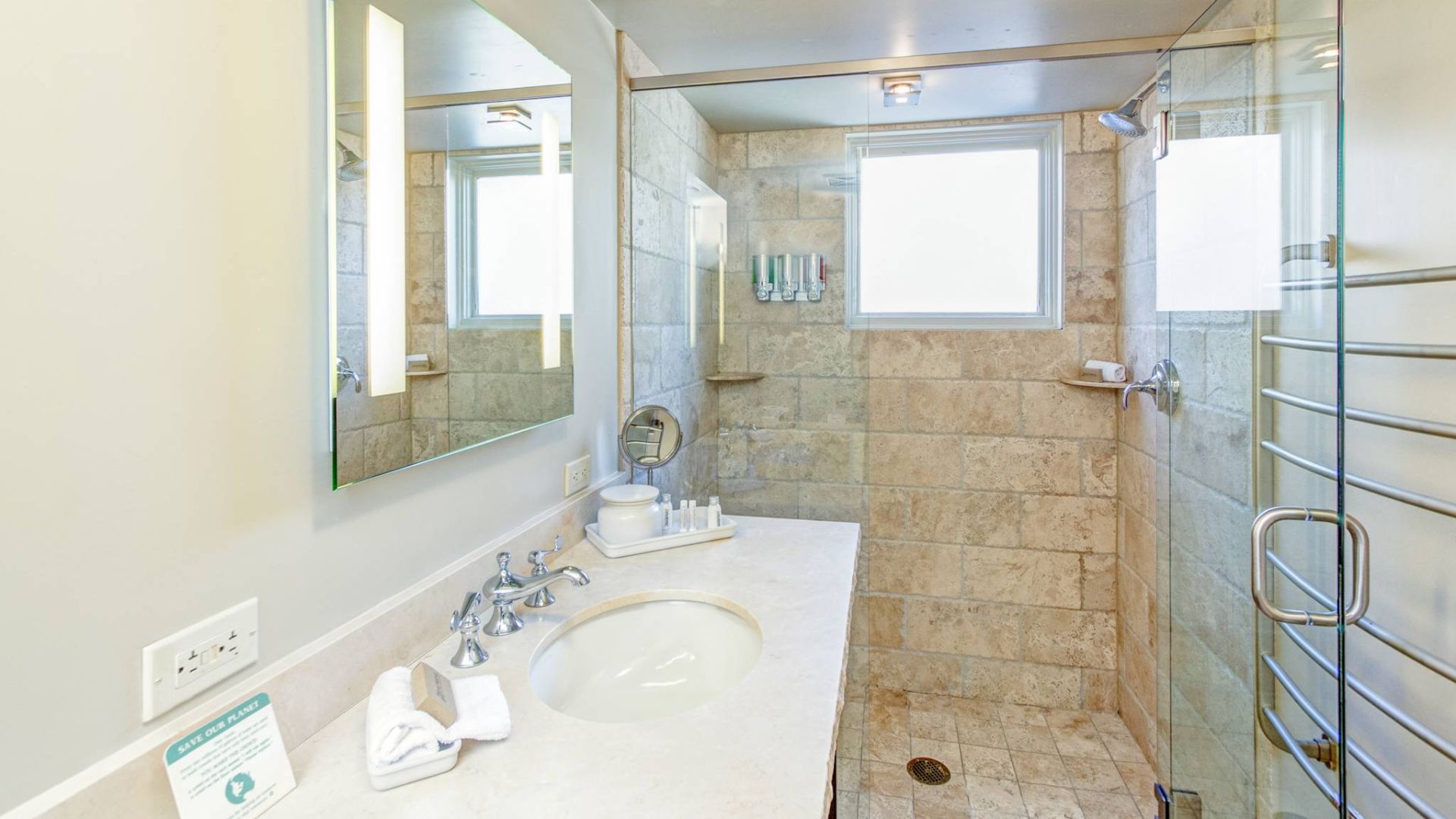 A modern bathroom with a shower, sink, mirror, and towels.