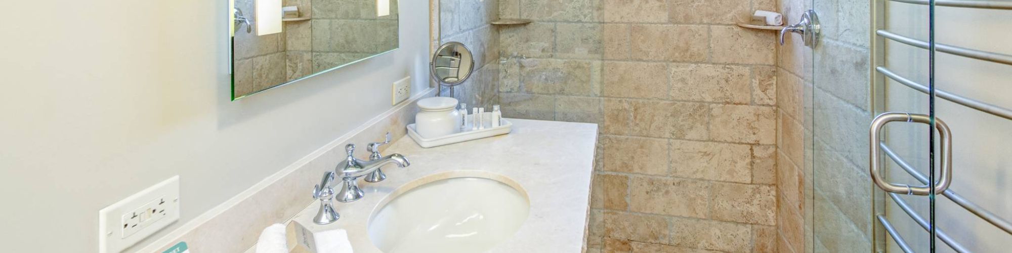 A modern bathroom with a shower, sink, mirror, and towels.