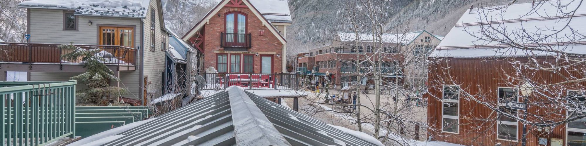 Snowy rooftops with a mountain backdrop and cloudy sky.