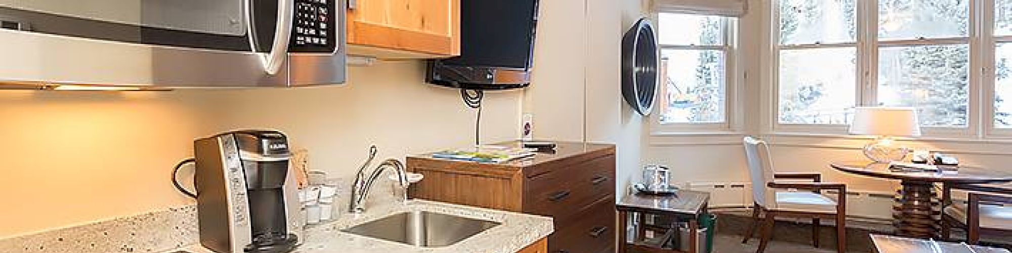 A modern kitchen with wooden cabinets, appliances, and a cozy dining area in the background.