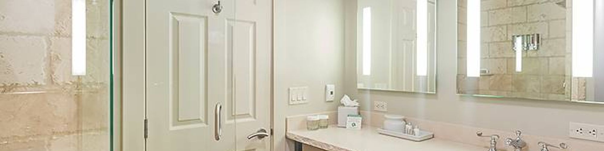 Modern bathroom with a glass shower, double sink, large mirror, and neutral colors.