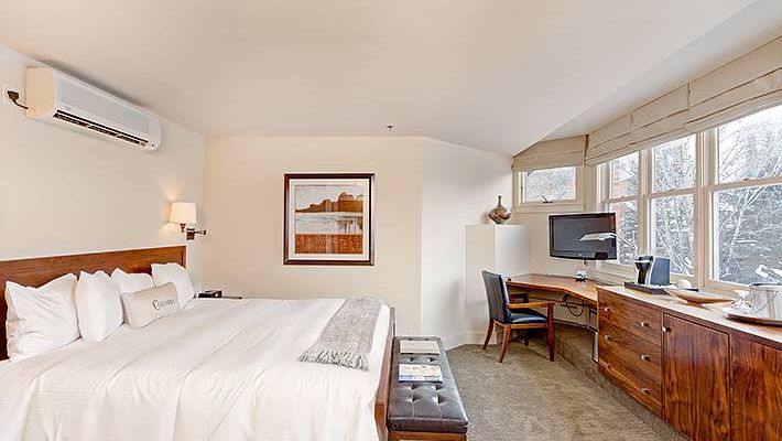 A cozy Hotel Columbia Telluride room with a bed, desk, TV, and a snowy view outside the window.