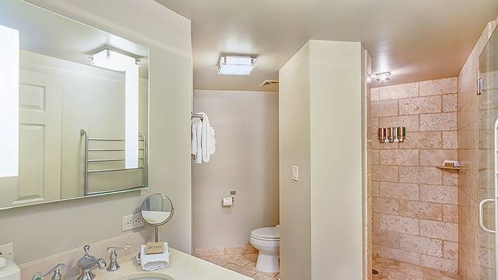 A clean bathroom with a sink, mirror, toilet, and shower area.