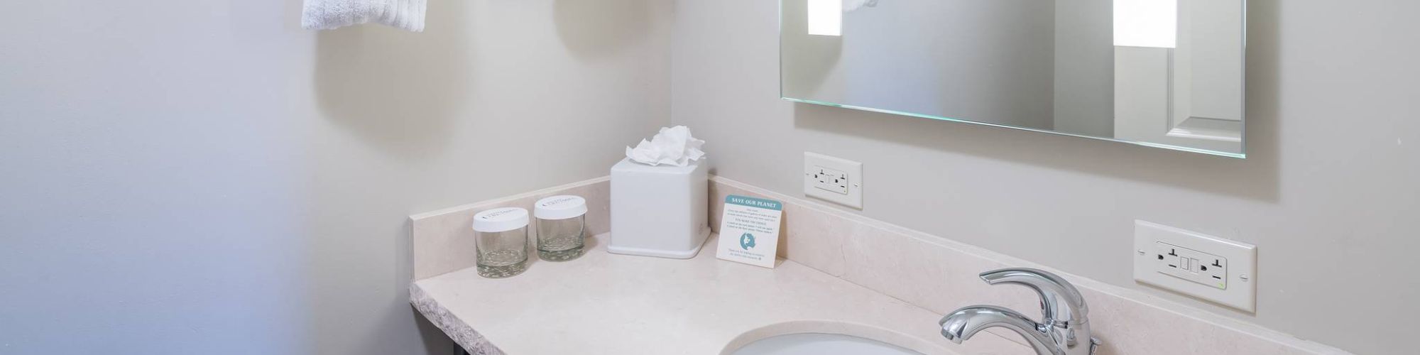 A neat bathroom with towels, mirror, sink, and toiletries.