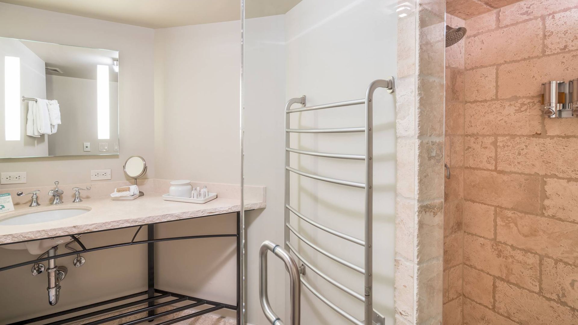 A modern bathroom with a shower, towel rack, and vanity mirror.