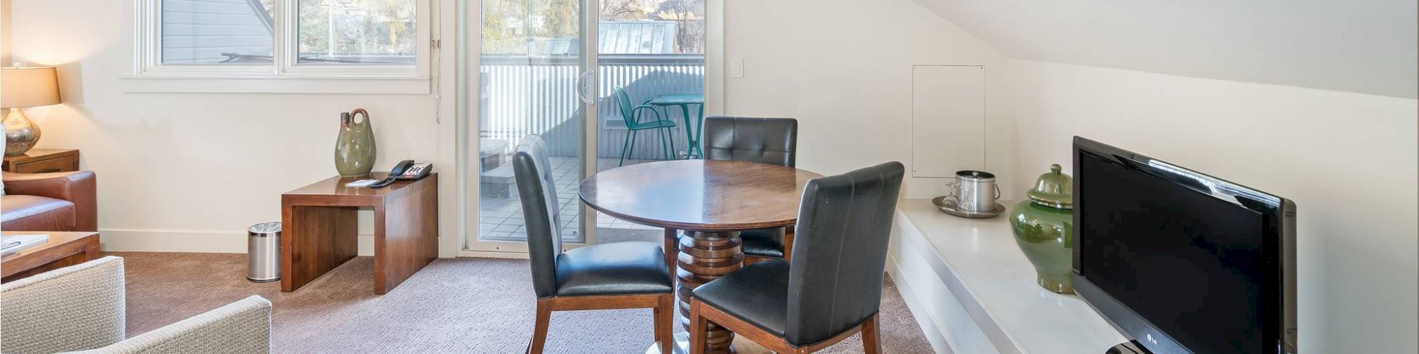 Bright room with dining table, chairs, TV, and ceiling windows.