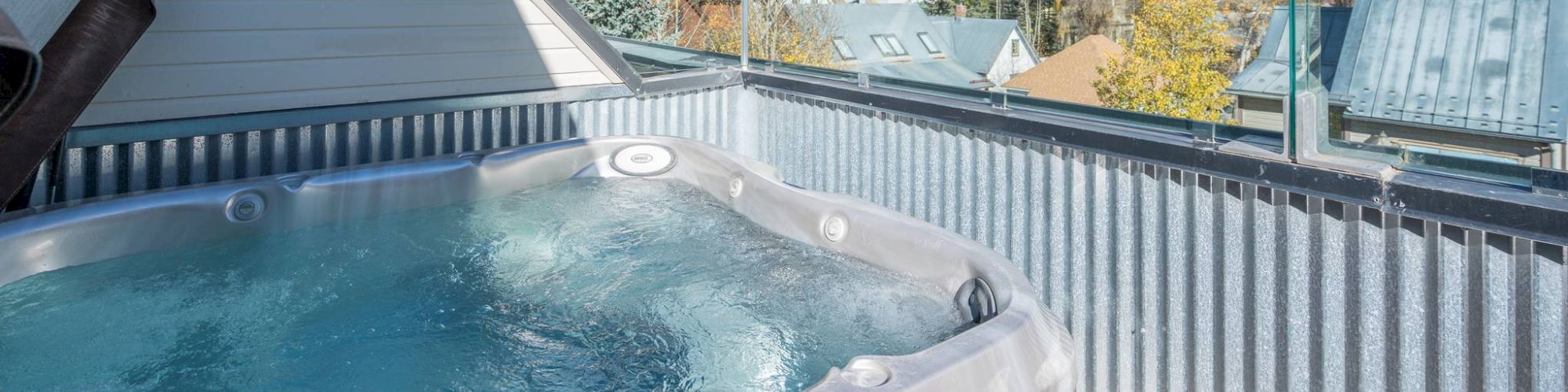 Hot tub on a deck with a view of autumn mountains and clear skies.