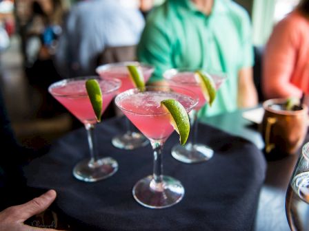 A tray with pink cocktails garnished with lime wedges.