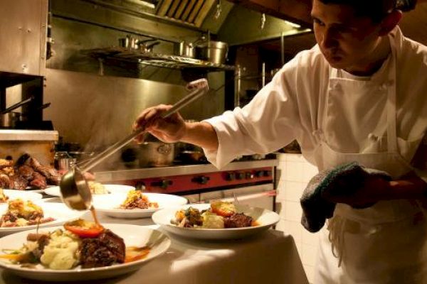 A chef is plating food in a professional kitchen.