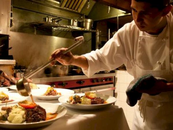 A chef is plating food in a professional kitchen.
