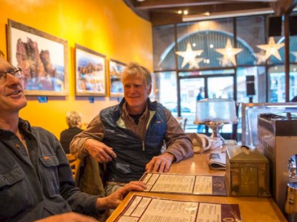 Two people are smiling and sitting at a table in a cozy cafe with star decorations.