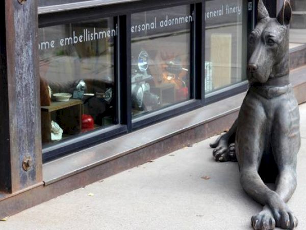 A large dog sculpture sits in front of a window display with various items.