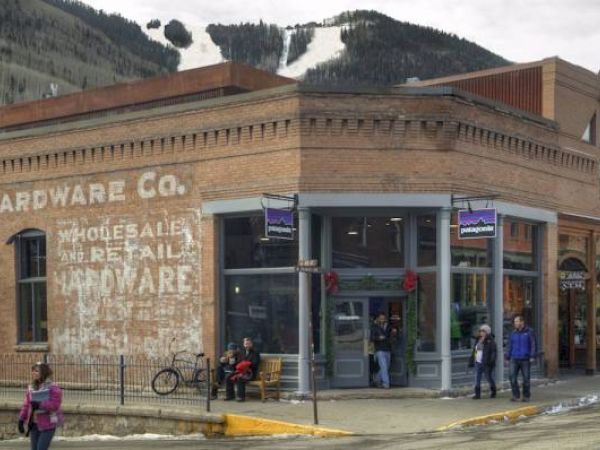An old building with "HARDWARE CO." sign, people walking outside, and snow-capped hill in the background.
