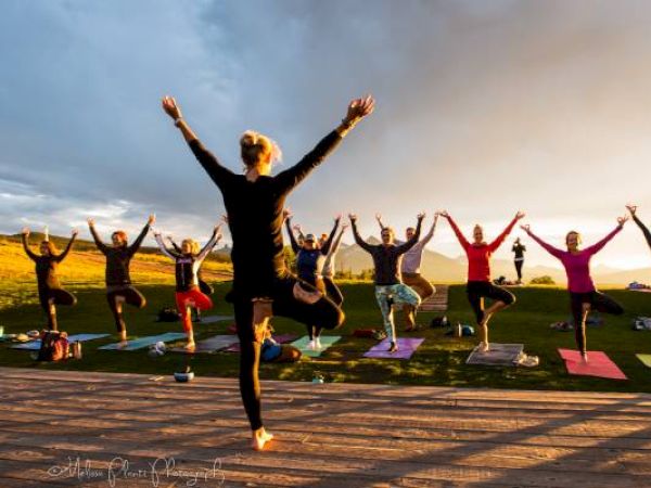 A group of people is doing yoga outside at sunset.