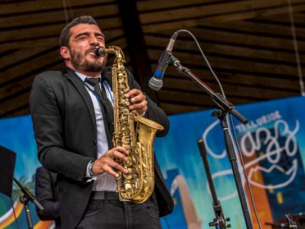 A man plays the saxophone on stage at a jazz event.