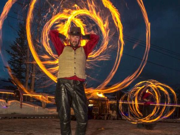 A person is performing with fire poi at night, creating circular trails of light.