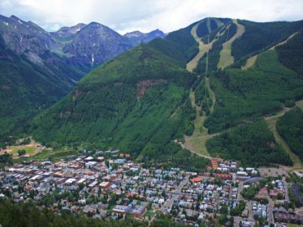 Aerial view of a mountain town with ski slopes in the background.
