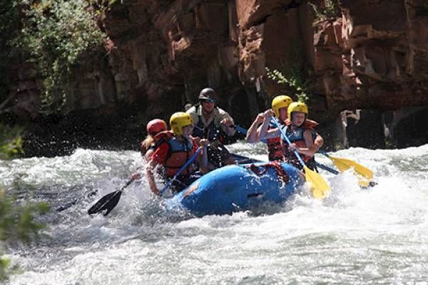 People are white-water rafting on a river, navigating through rapids.