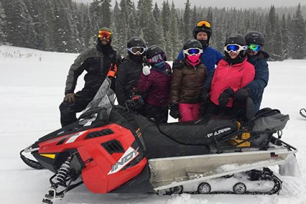 A group of people with a snowmobile are enjoying winter sports together.