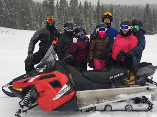 A group of people with a snowmobile are enjoying winter sports together.