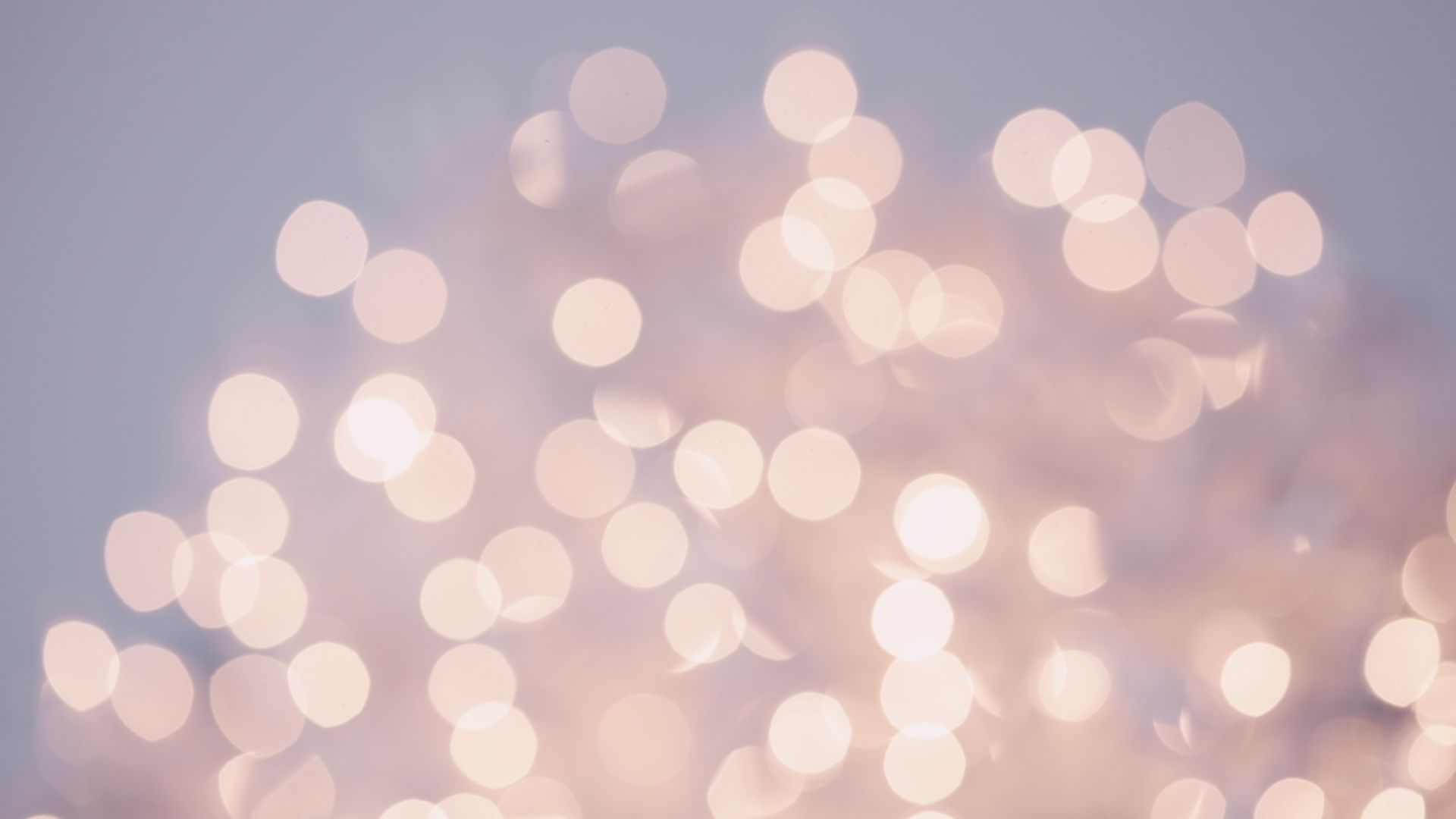 The image shows an out-of-focus, bokeh effect with many circular light spots in soft hues of white and pink against a light purple background.