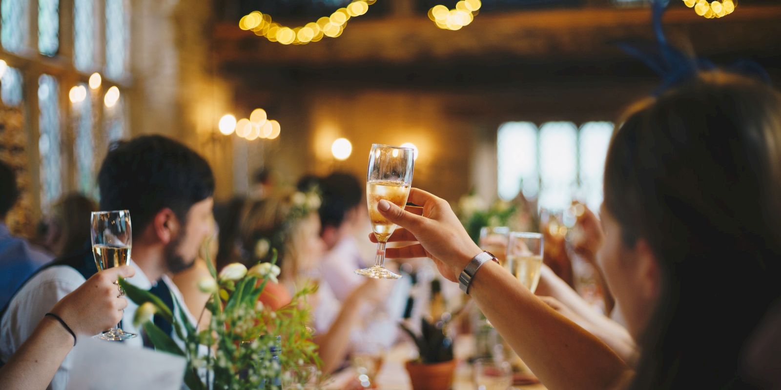 People raising glasses in a toast at a festive gathering, with warm lighting at Hotel Columbia Telluride.