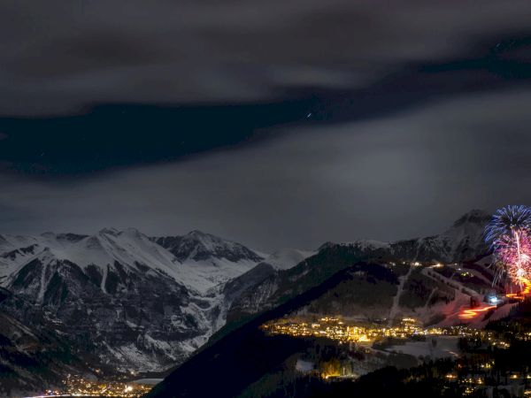 A stunning night view of mountains with fireworks and a lit-up town below.