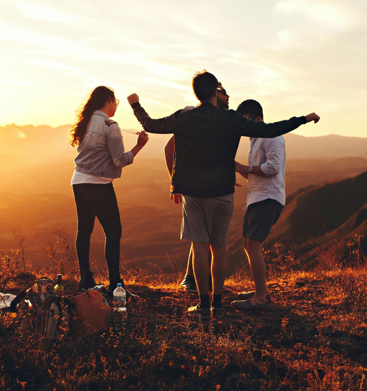 Three people enjoying a sunset on a hill, with warm light embracing them in Telluride Colorado.