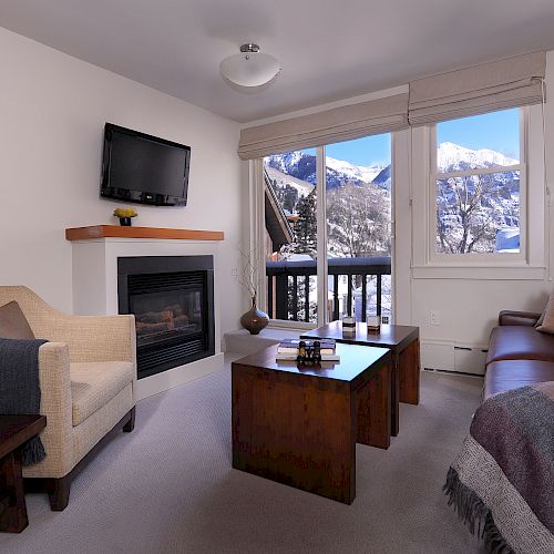 Cozy living room with a fireplace, sofa, mountain view from the window, and a TV.